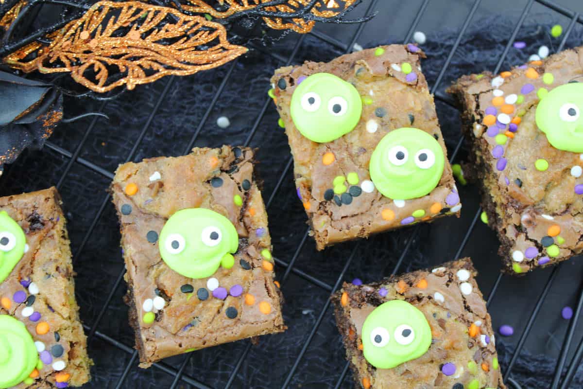 close up of chocolate brownies with sprinkles and little green alien heads on top